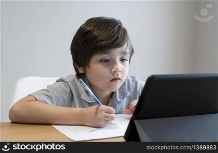 Kid self isolation using tablet for his homework,Child doing using digital tablet searching information on internet during covid-19 lock down,Social Distancing ,E-learning and online education