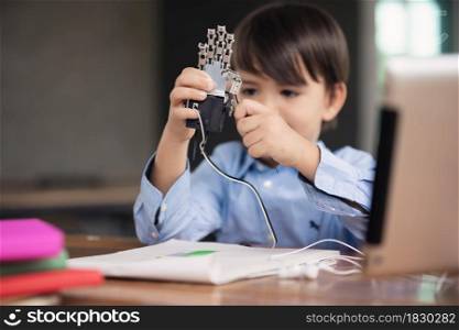 Kid self isolation using tablet for his homework, child playing with robotic arm alone during covid 19 lock down,Home schooling,Social Distance,E-learning online education.