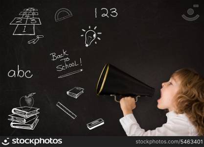 Kid shouting through vintage megaphone against blackboard