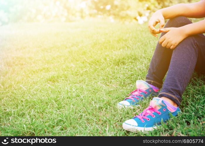 Kid sitting on the green grass in the park with copy space