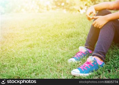 Kid sitting on the green grass in the park with copy space