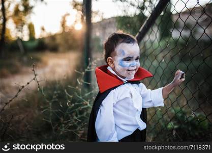 Kid smiling costumed of dracula to halloween on the forest