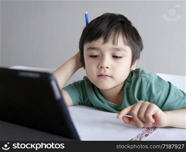 Kid stay at home watching cartoon on teblet, Child using digital tablet searching information on internet for his homework during covid-19 lock down,Social Distancing, learning online education