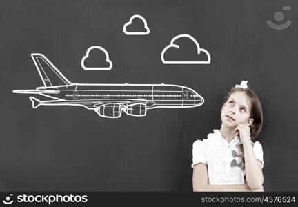 Kid student girl against school blackboard having good idea. Thoughtful girl standing at blackboard