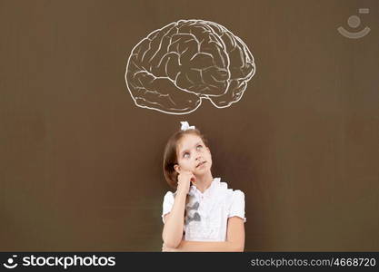 Kid student girl against school blackboard having good idea. Thoughtful girl standing at blackboard