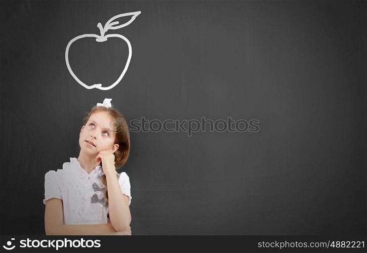 Kid student girl against school blackboard having good idea. Thoughtful girl standing at blackboard