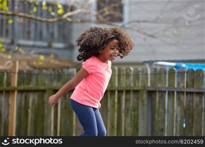 Kid toddler girl jumping on a playground in the backyard latin ethnicity