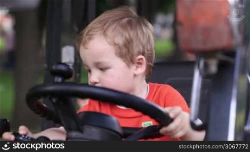 Kid turns the wheel of the tractor