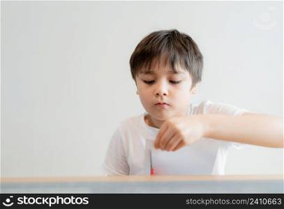Kid using scissors cutting white paper , schoolboy making art and craft for his homework,Child learning how to use the scissors cut the paper,Children learn and play at home, Home school concept