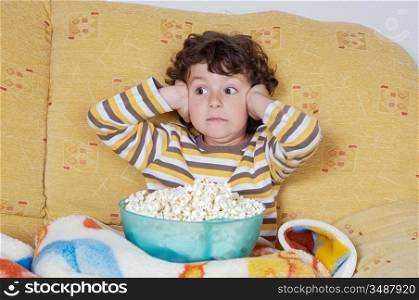 Kid watching a scary movie eating pop corn