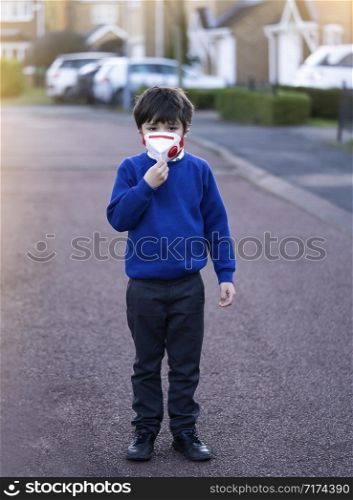 Kid wearing protective face mask for pollution or virus, Mixed race asian - caucasian 6 year old, Child wearing protection mask while walking to school, Concept for Corona or Coronava virus and pm 2.5