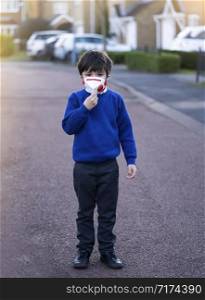 Kid wearing protective face mask for pollution or virus, Mixed race asian - caucasian 6 year old, Child wearing protection mask while walking to school, Concept for Corona or Coronava virus and pm 2.5