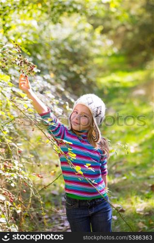 kid winter girl picking mulberry berries in the forest with wool cap