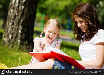 Kid with mom. Image of cute girl and her mother playing in park