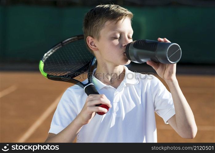 kid with racket shoulder drinking water