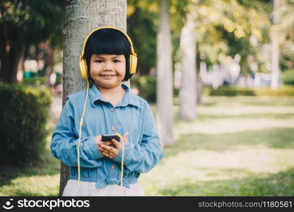 Kids concept and technology - smiling girl with headphones listening to music