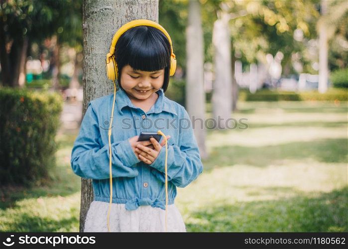 Kids concept and technology - smiling girl with headphones listening to music