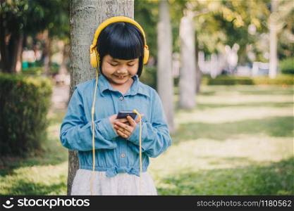 Kids concept and technology - smiling girl with headphones listening to music