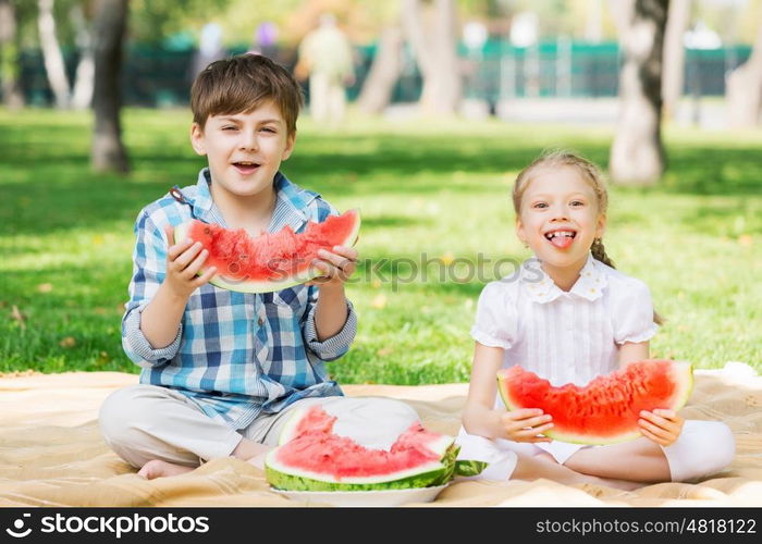 Kids eating watermelon. Cute kids in park eating juicy watermelon