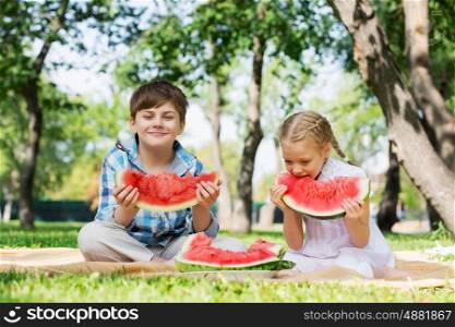 Kids eating watermelon. Cute kids in park eating juicy watermelon