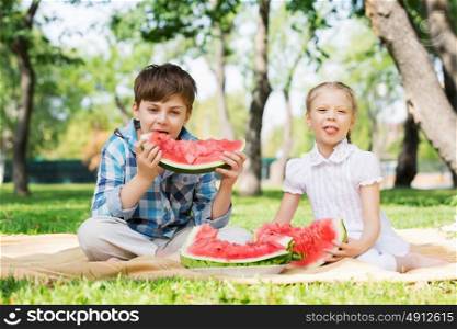Kids eating watermelon. Cute kids in park eating juicy watermelon