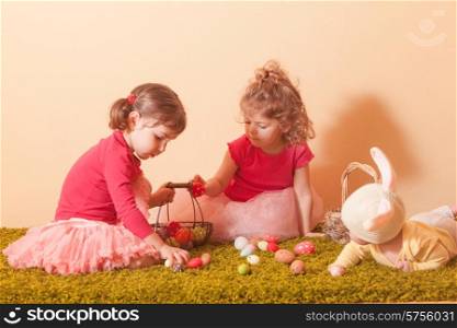 Kids gather colorful eggs to the baskets on Easter Egg hunt. Girls on an Easter Egg hunt