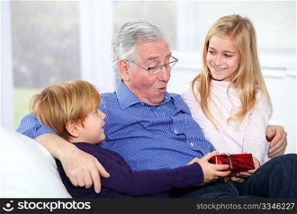 Kids giving birthday gift to their grandfather