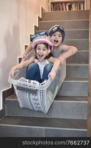 Kids having fun sledding down stairs in a storage box