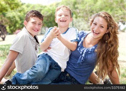 Kids having fun with mum and smiling at camera as they spend out day in park
