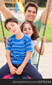 kids having fun with their father in the park and smiling at camera