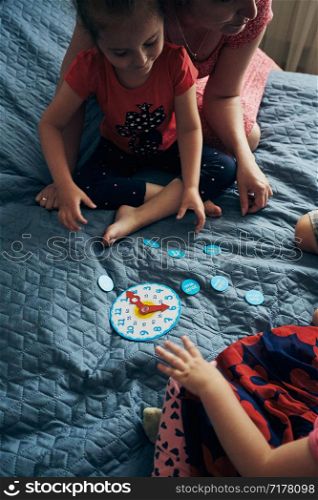 Kids learning how to tell time from clock and set the hands in the correct position. Teaching preschoolers tell time. Candid people, real moments, authentic situations