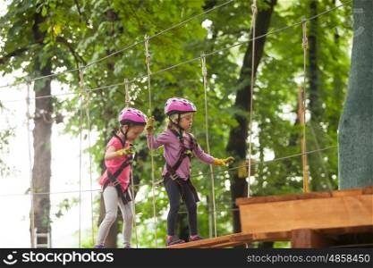 Kids on obstacle course in adventure park in mountain helmet and safety equipment. The obstacle course in adventure park