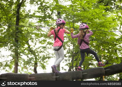 Kids on obstacle course in adventure park in mountain helmet and safety equipment. The obstacle course in adventure park