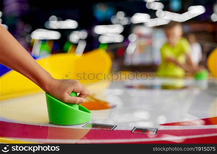 Kids play air hockey in entertainment center. Children having fun, sport competition on playground, happy childhood. Kids play air hockey in entertainment center