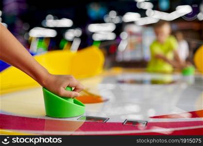Kids play air hockey in entertainment center. Children having fun, sport competition on playground, happy childhood. Kids play air hockey in entertainment center