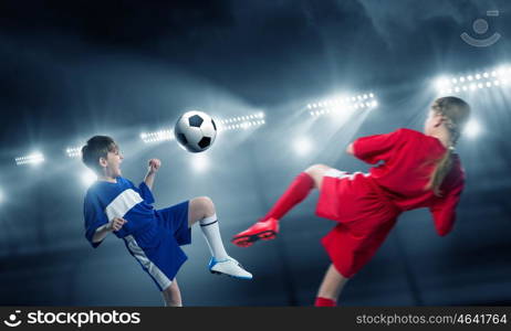 Kids play soccer on stadium . Kid boy and girl on soccer stadium fighting for ball