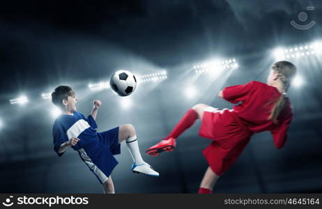 Kids play soccer on stadium . Kid boy and girl on soccer stadium fighting for ball