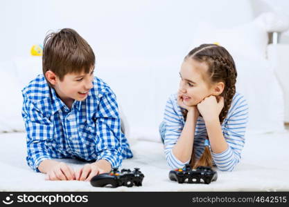 Kids playing game console. Cute kids lying on floor playing games on joystick