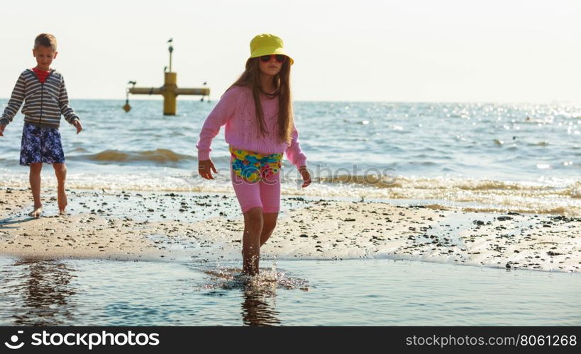 Kids playing outdoor on beach.. Joyful active childhood. Playful kids playing near water on seaside. Children having fun on summer beach. Young tourists spending actively time.