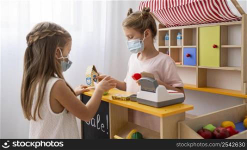 kids playing together indoors while wearing medical masks