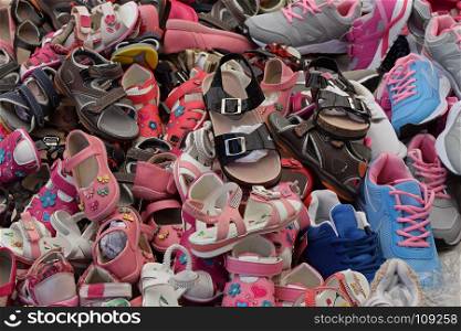 Kids shoes for sale at street market. Assorted pile of footwear.