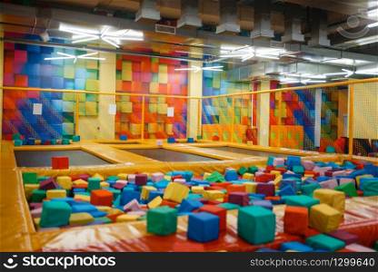 Kids trampoline and soft cubes on playground in entertainment center, nobody. Play area for children indoors, playroom