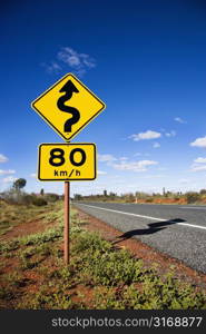 Kilometer per hour speed limit and curve ahead road signs in rural Australia.