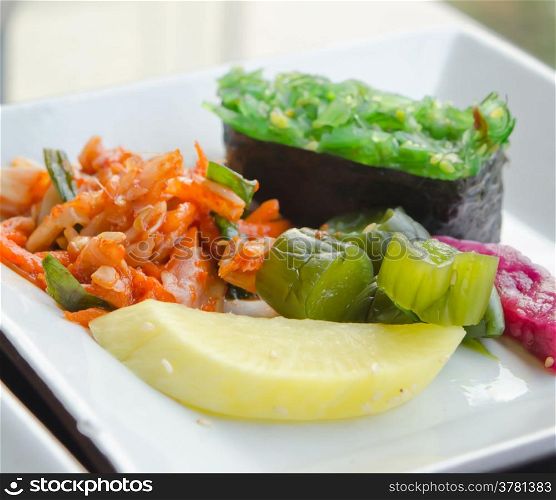kimchi and pickled vegetable , Chuka seaweed sush on white plate