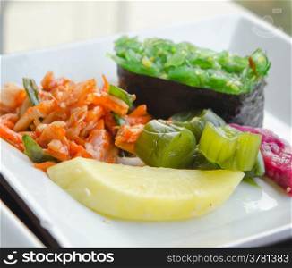 kimchi and pickled vegetable , Chuka seaweed sush on white plate