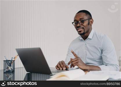 Kind boss, businessman in formal wear has online meeting in zoom. African american man is speaking in front of camera. Distant work at home concept. Remote conference or lesson.. Kind boss, businessman in formal wear has online meeting in zoom. African man in front of camera.