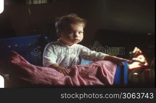 Kind sitzt im Bett und greift mit der Hand
