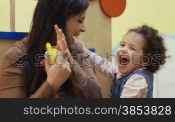Kindergarten: teacher playing and laughing with little young girl