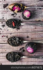 kinds of tea infuser in tea spoons on wooden background. Flavored blooming tea