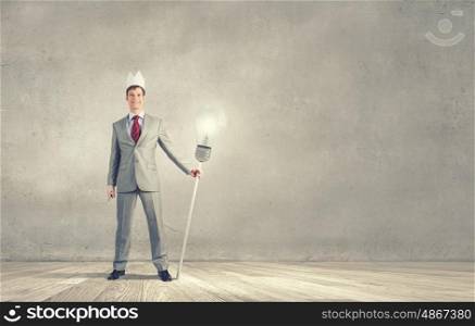 King of creativity. Young businessman in paper crown lifting barbell above head